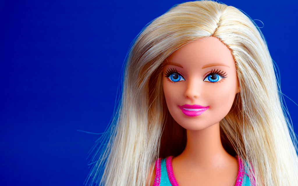 A Close-up shot of a blonde barbie looking past the camera. She is against a blue background.